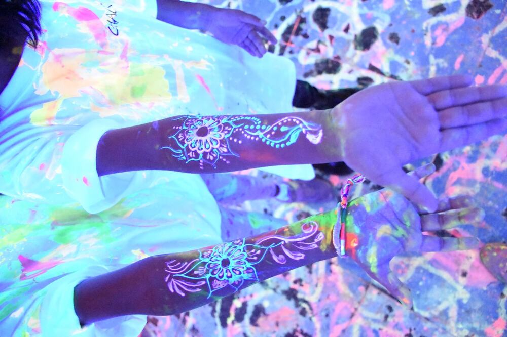 Neon henna art glowing under blacklight