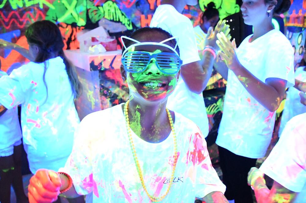 Kids covered in neon paint laughing in the blacklight room