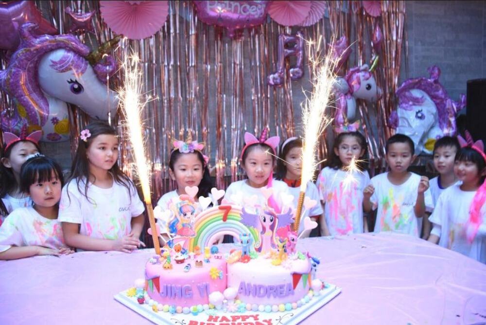 Birthday cake with sparkler candle surrounded by kids